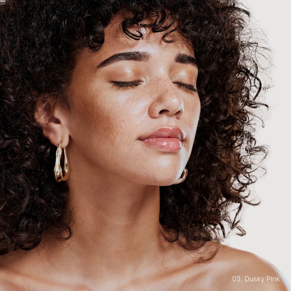 Femme aux yeux fermés et lèvres brillantes. Produit appliqué : 03 Dusky Pink.