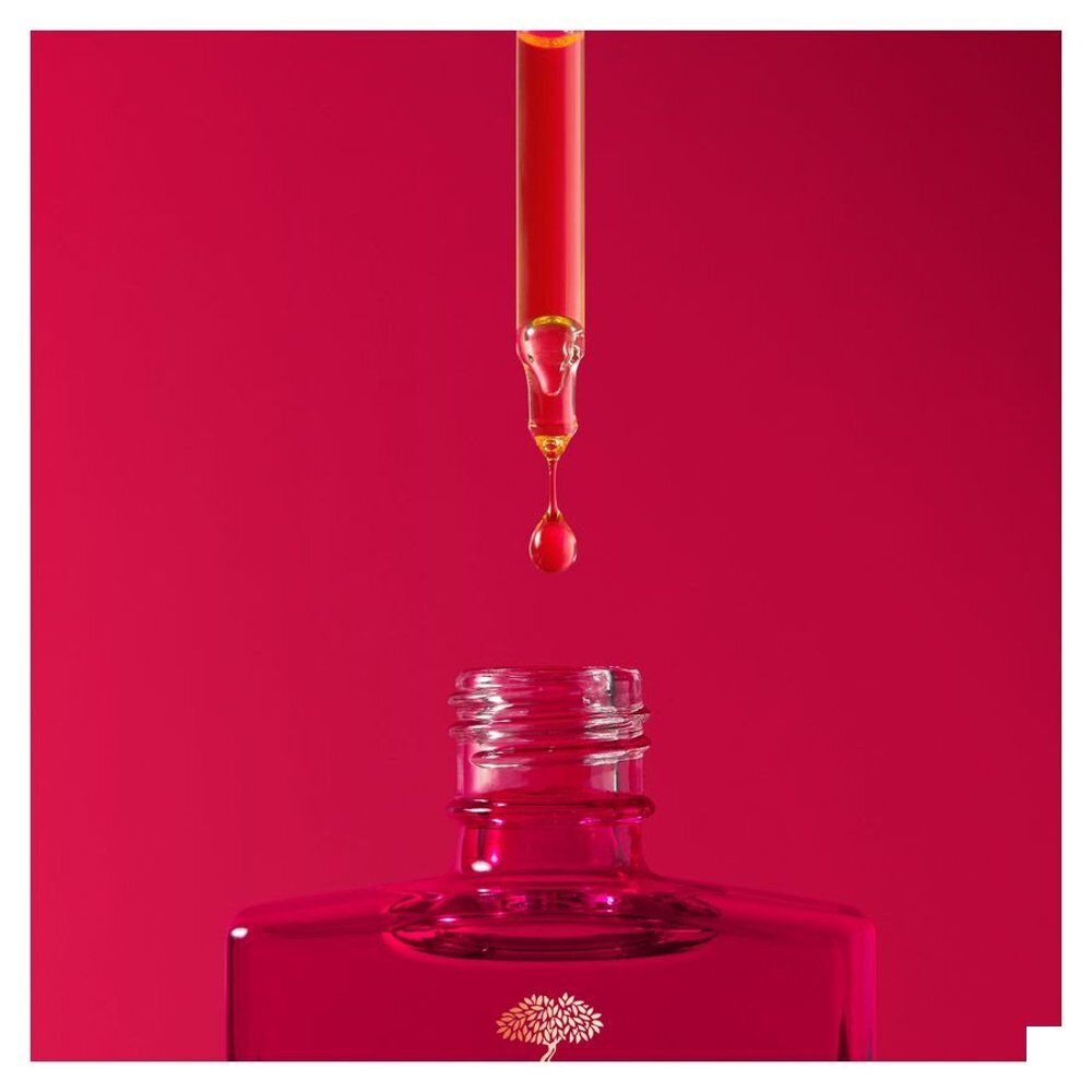 Femme tenant un flacon Nuxe Merveillance Lift et une pipette de sérum.