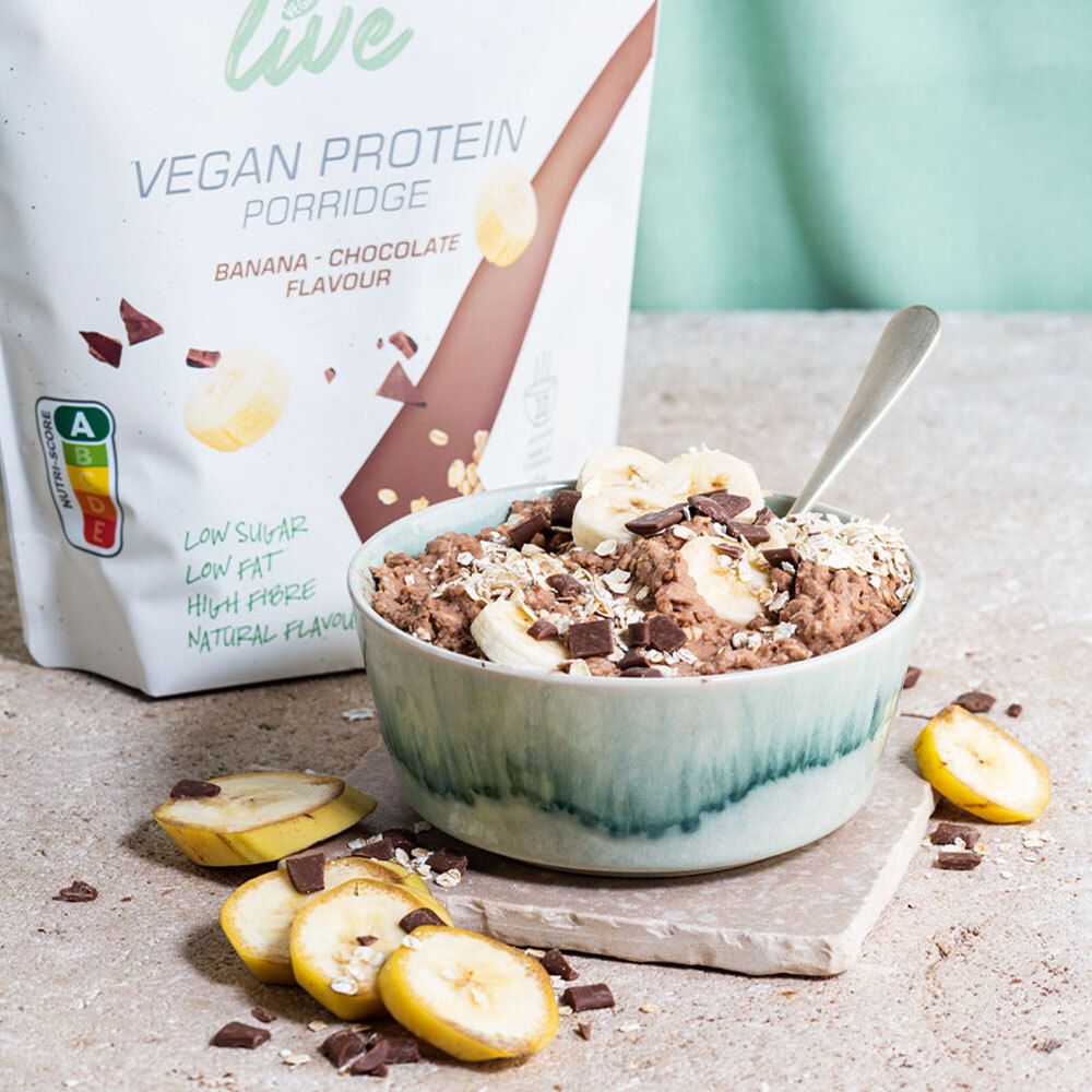 Bol de porridge avec tranches de banane et morceaux de chocolat. En arrière-plan : sachet de porridge protéiné végétalien "etixx live".