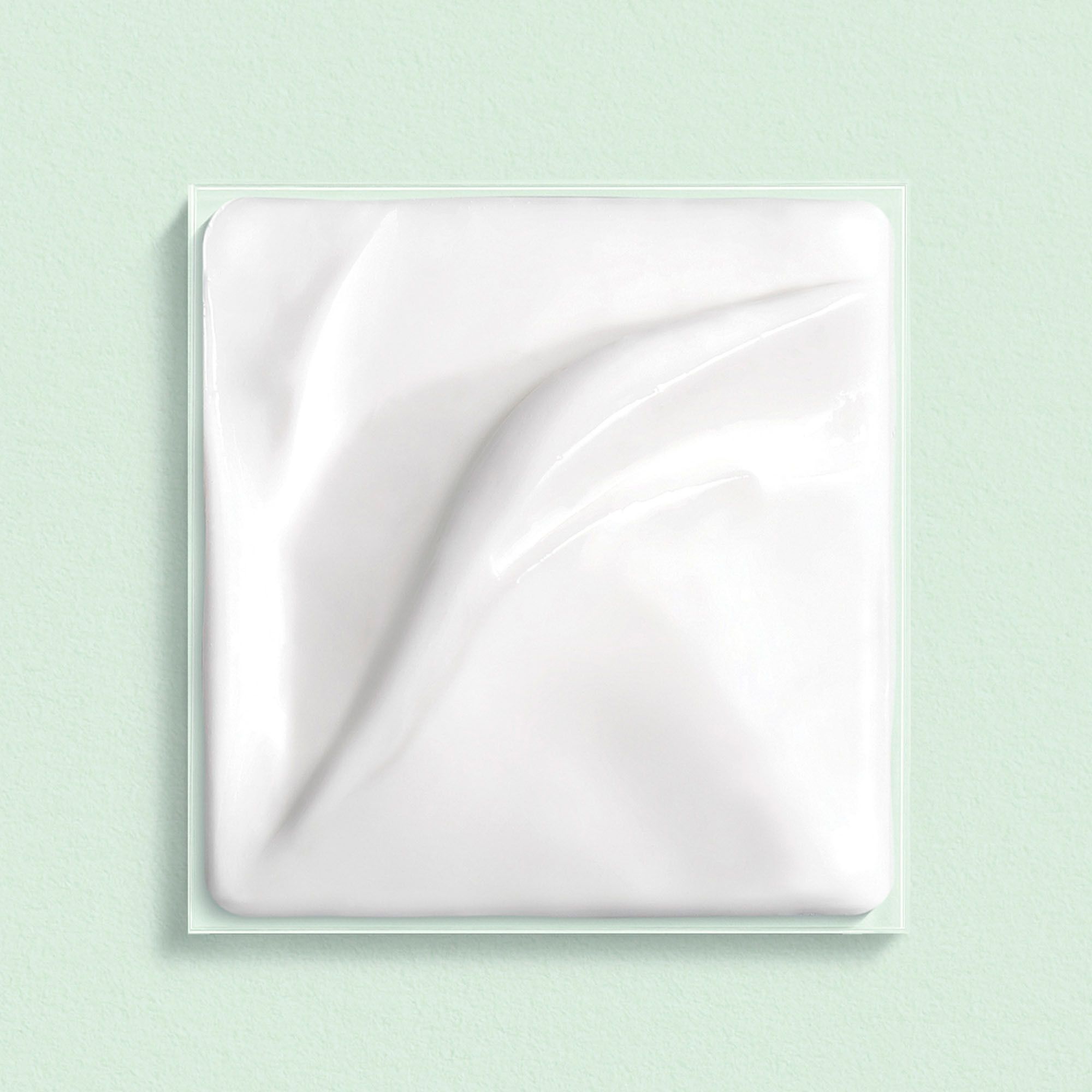 Emballage carré transparent avec crème blanche. Surface de la crème avec motif ondulé.