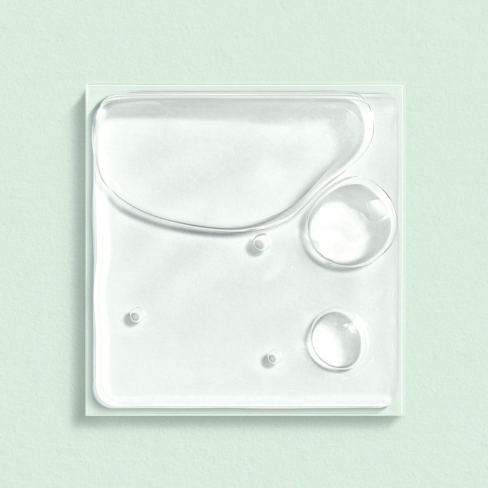 Plaque carrée transparente avec gouttes de liquide. Plusieurs gouttes de tailles différentes.