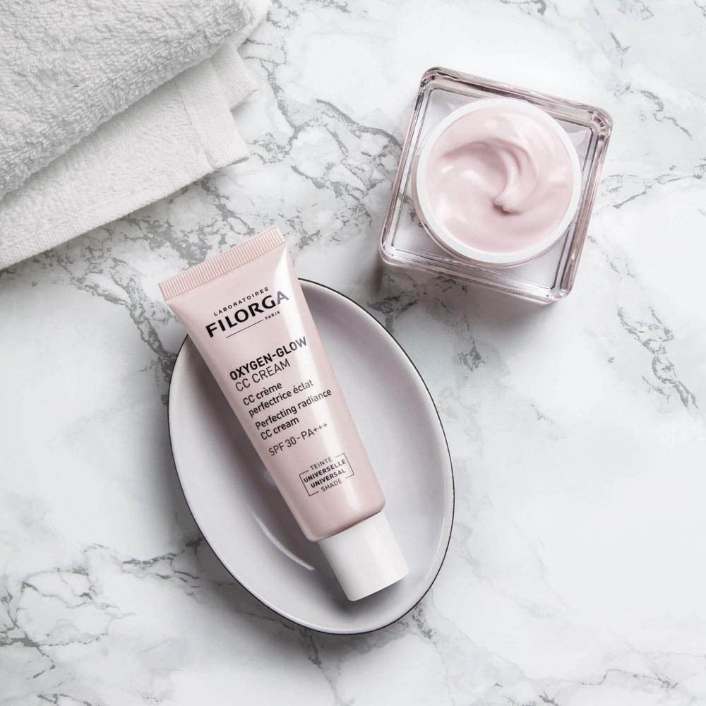 Deux tubes FILORGA Oxygen-Glow CC Cream. Sur fond noir. Un pot de crème à côté.