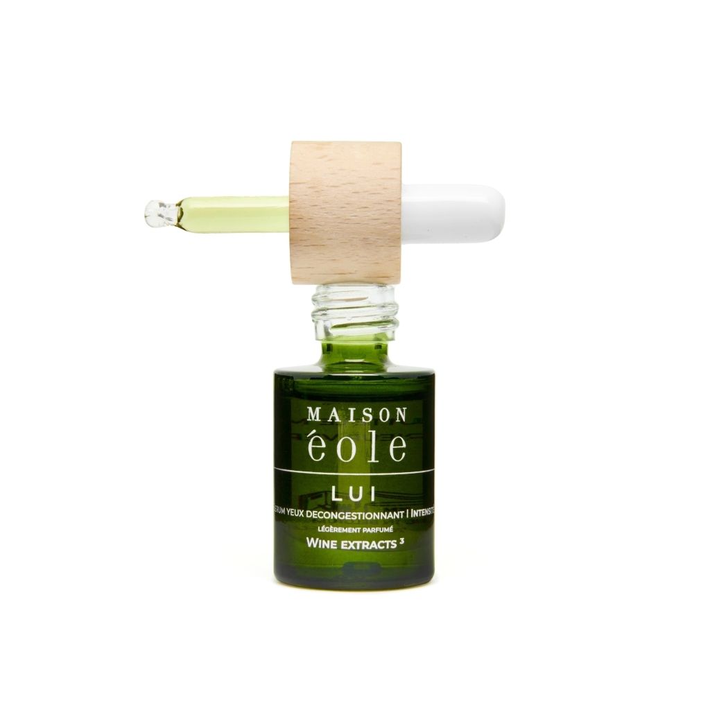 Flacon en verre vert avec bouchon en bois et pipette. Pipette avec liquide. Inscription: Maison Éole, Lui, Sérum Yeux Décongestionnant Intensité.