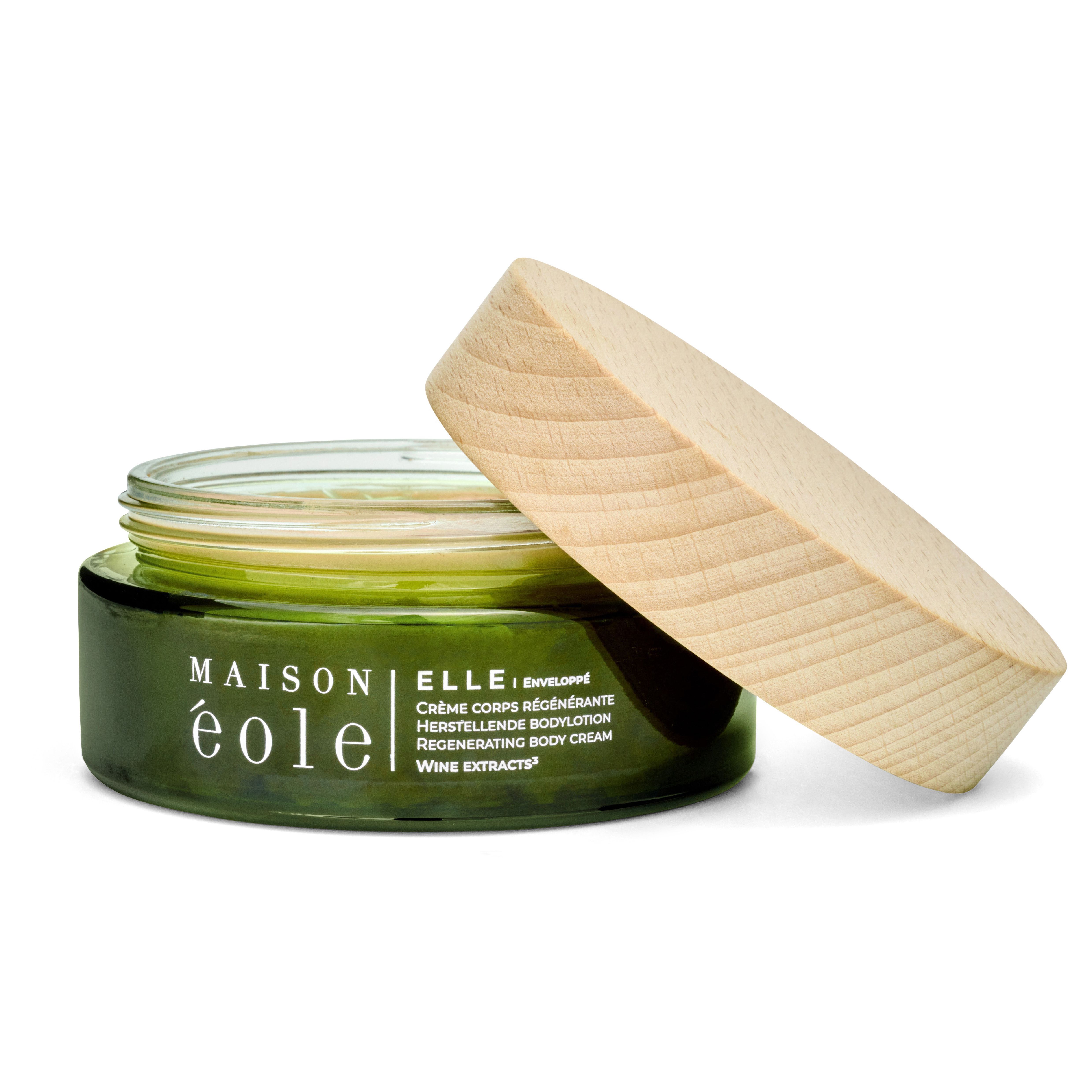Pot en verre vert avec couvercle en bois, couvercle ouvert. Inscription: Maison éole, Crème Corps Régénérante, Herstellende Bodylotion, Regenerating Body Cream.