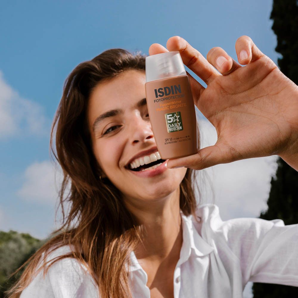 Femme tenant ISDIN Fotoprotector Magic Bronze. Crème solaire appliquée sur les doigts. Gros plan.