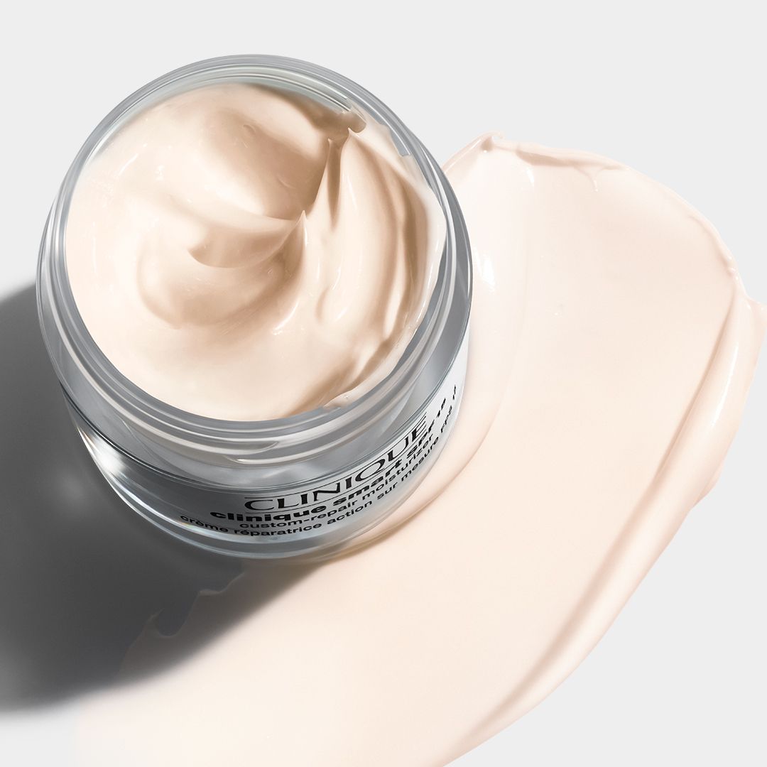 Pot en verre avec crème et texture crémeuse. Sur une surface claire. Texte : CLINIQUE.