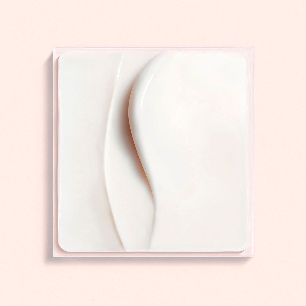 Gros plan d'une crème blanche sur fond rose. Crème de forme carrée avec des lignes ondulées.