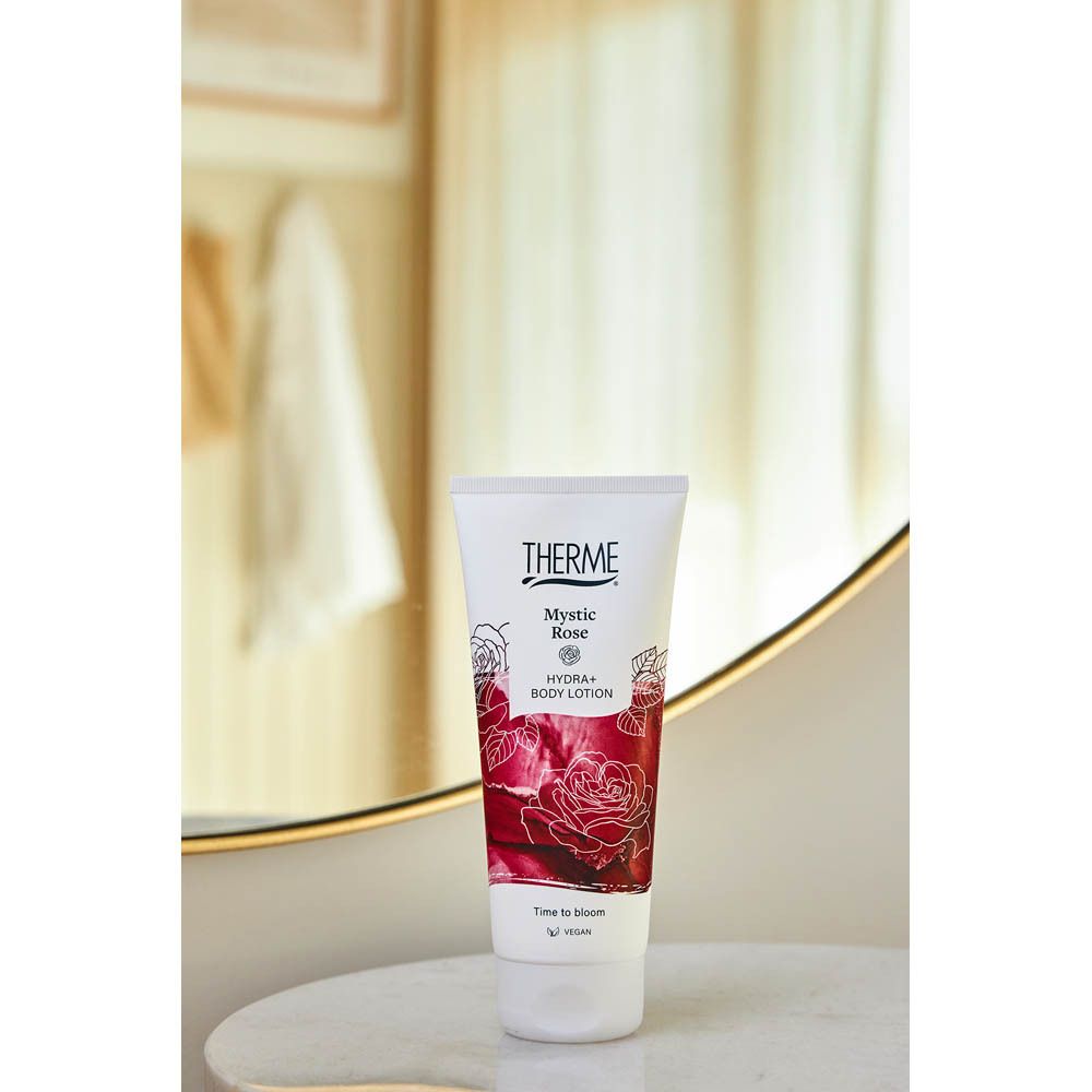 Tube de lotion corporelle THERME Mystic Rose Hydra+ sur une table en marbre devant un miroir.