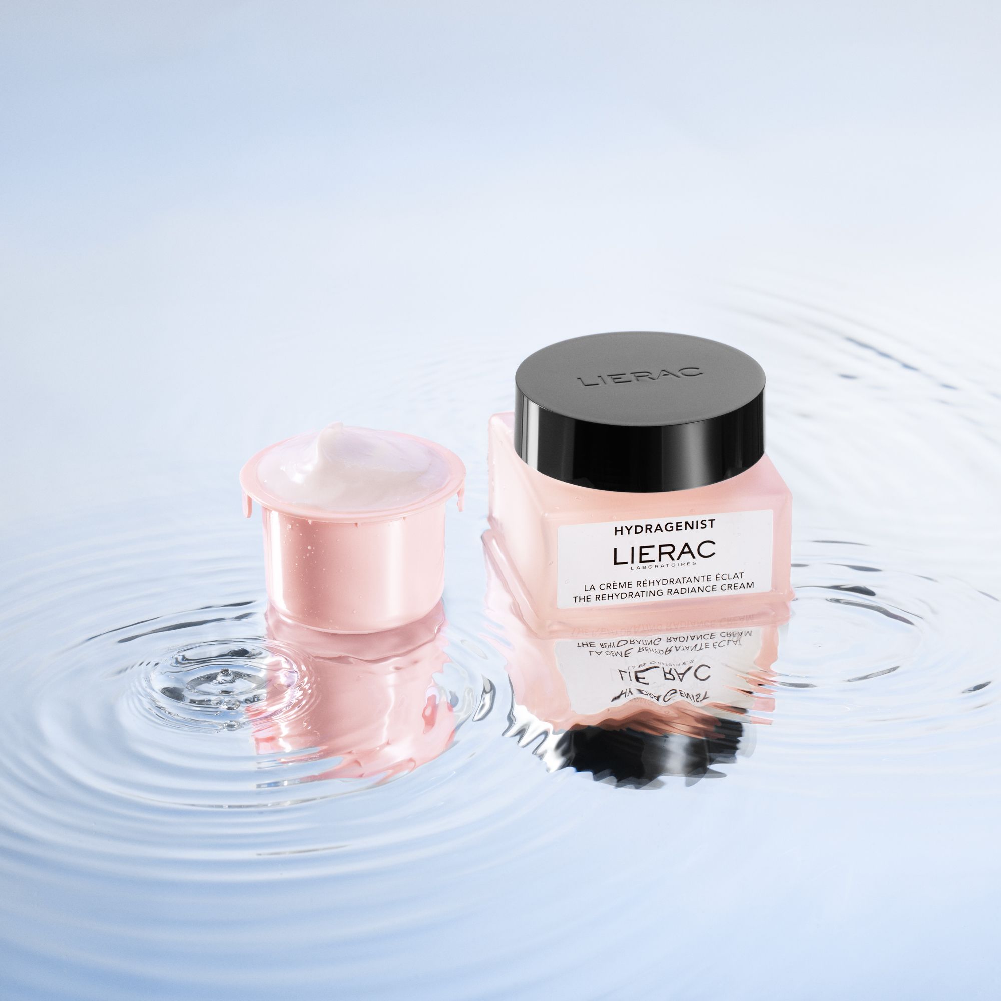 Pot de crème et récipient rose sur une surface réfléchissante. Marque: LIERAC. Récipient rempli de crème.