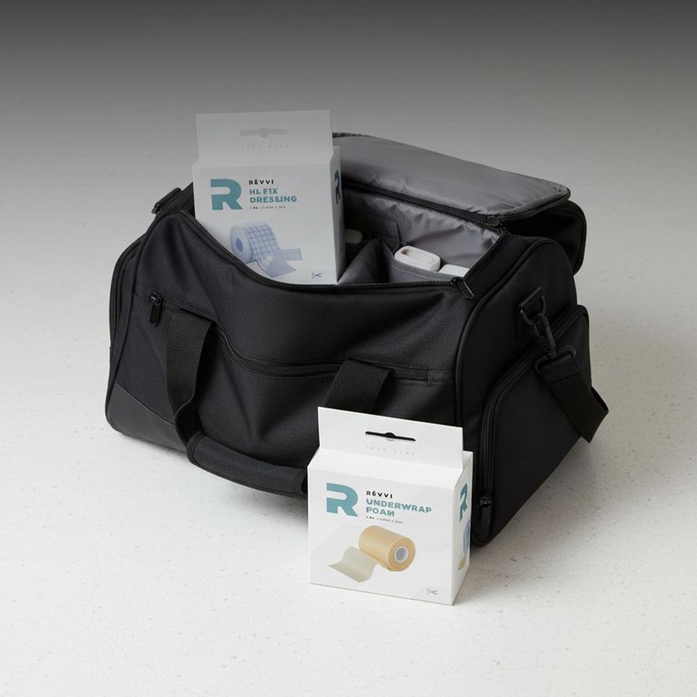 Sac de sport avec deux emballages de produits. Visible: emballage Hi-Fix Dressing et Unterwrap Foam. Logo Révi.