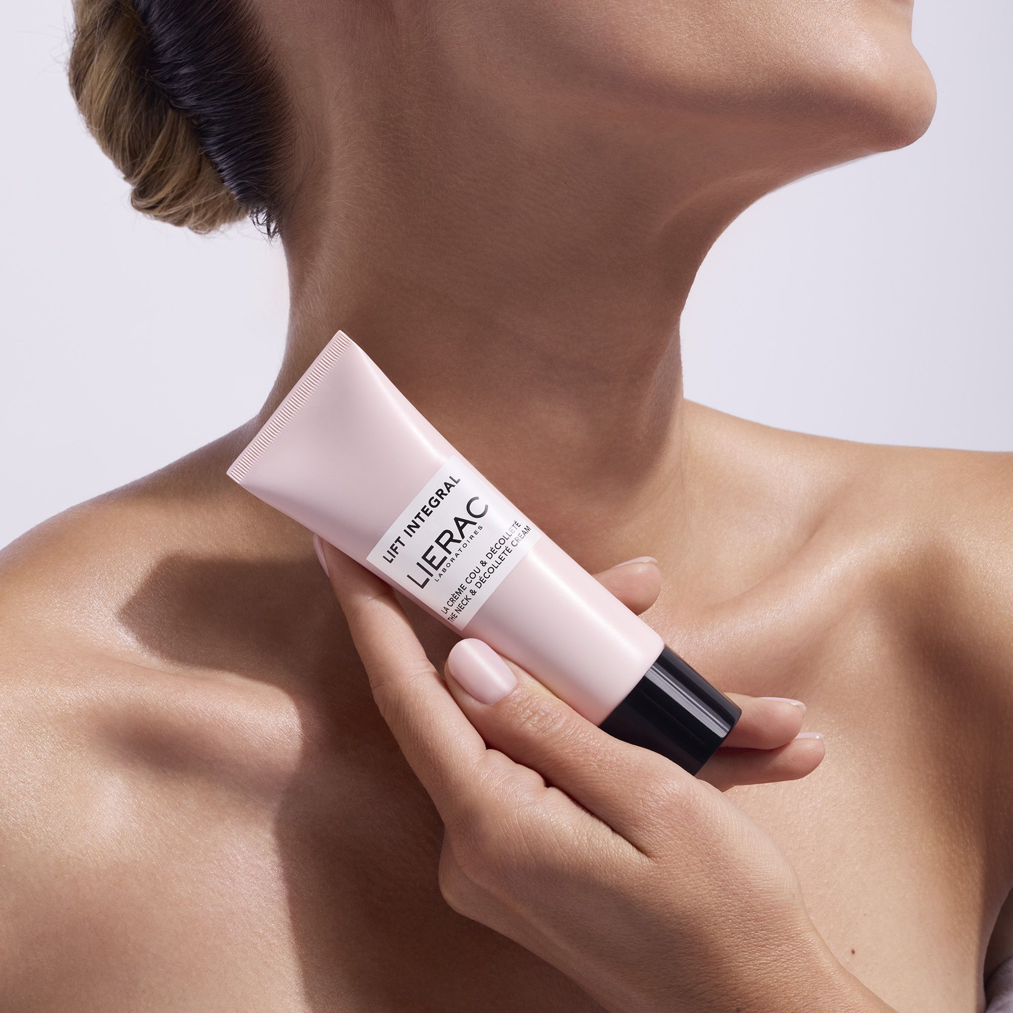 Personne tenant un tube rose avec bouchon noir. Inscription: Lift Integral, Lierac.