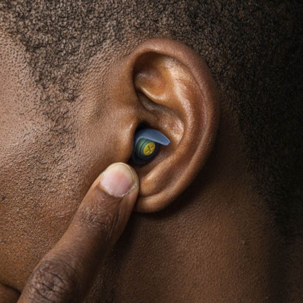 Bouchon d'oreille dans l'oreille. Un doigt touche l'oreille. Le bouchon est bleu.