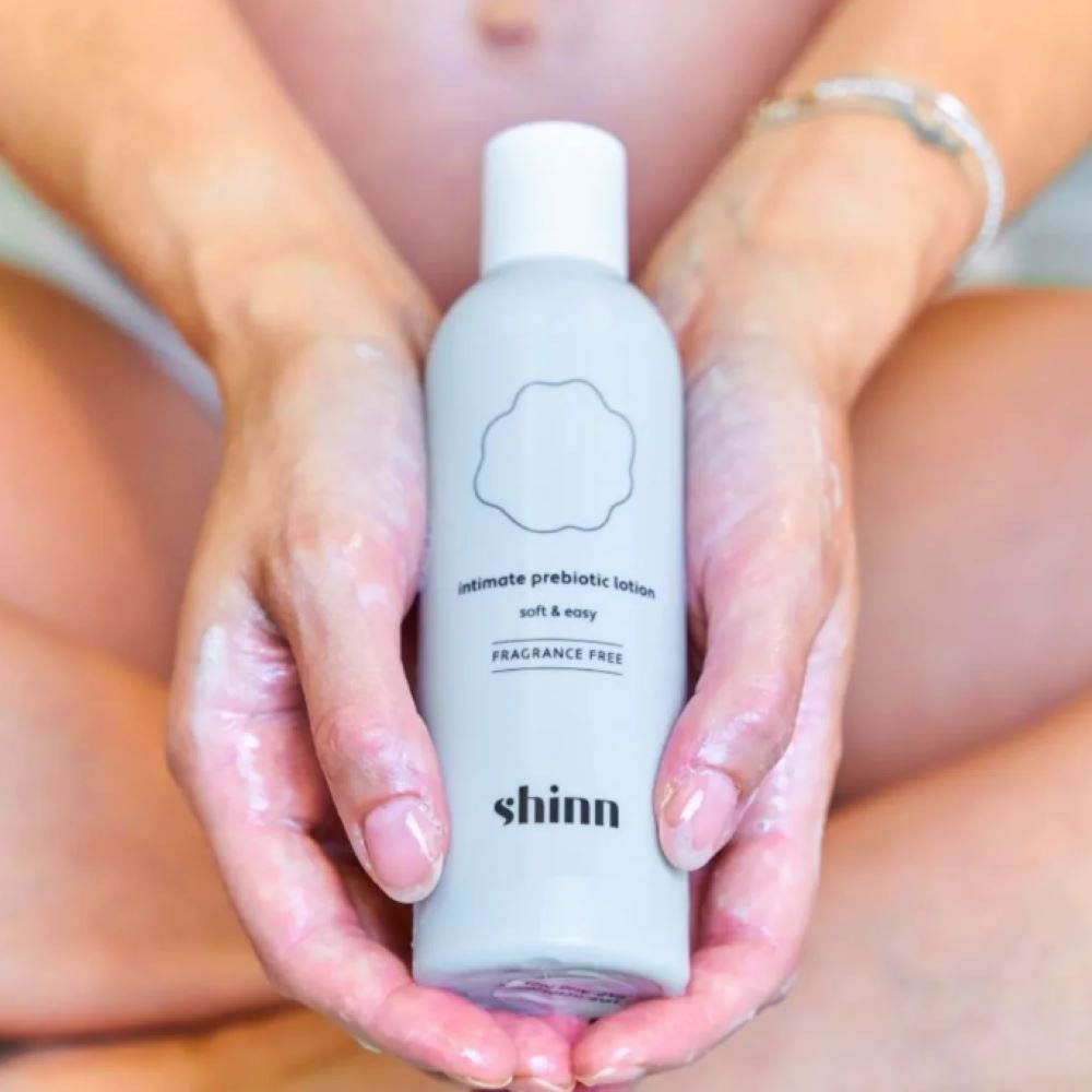 Mains tenant un flacon. Inscription : shinn, Intimate prebiotic lotion, soft & easy, Sans parfum.