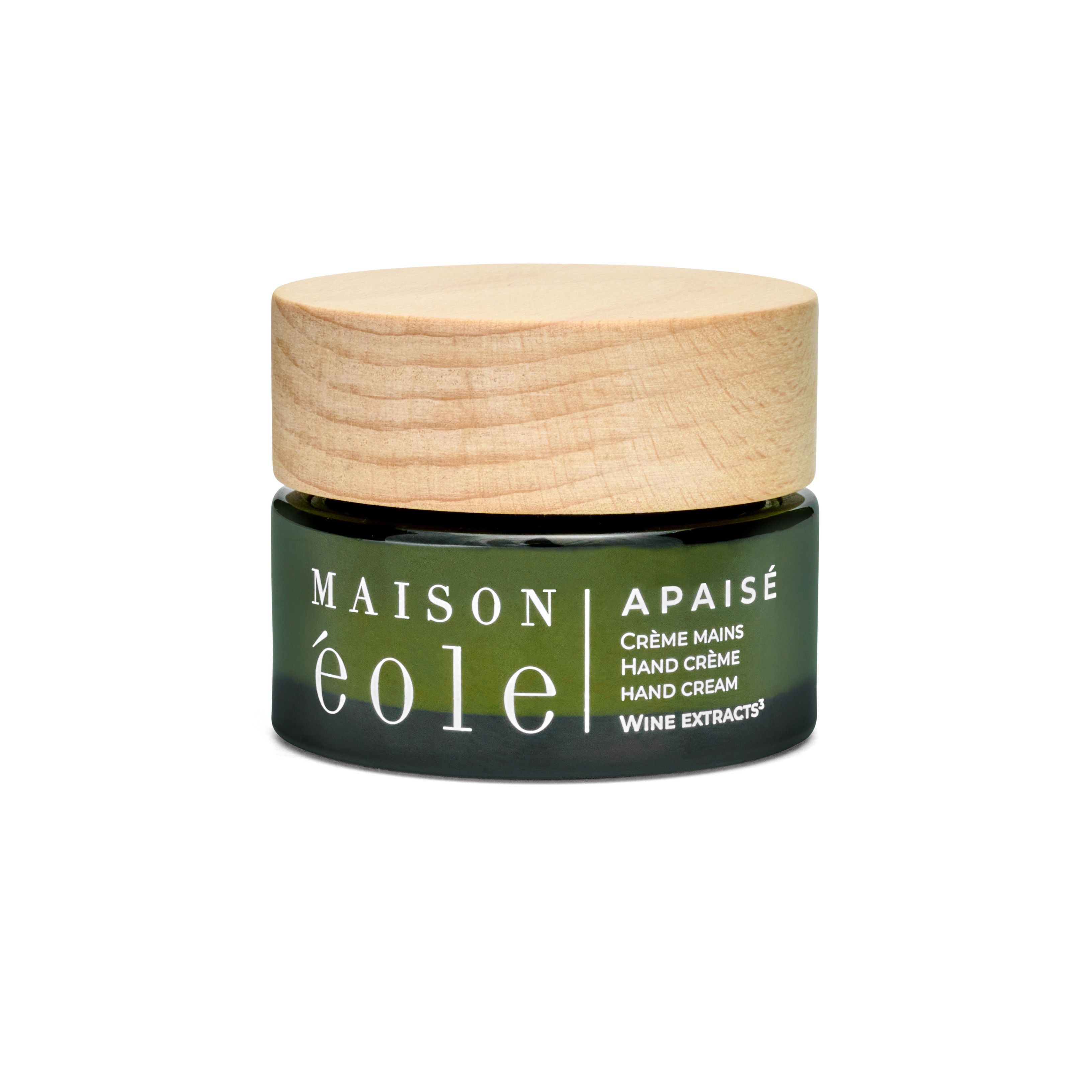 Pot de crème pour les mains en verre vert avec couvercle en bois. Inscription : Maison Éole, Apaisé, Crème Mains, Hand Crème, Hand Cream, Wine Extracts.