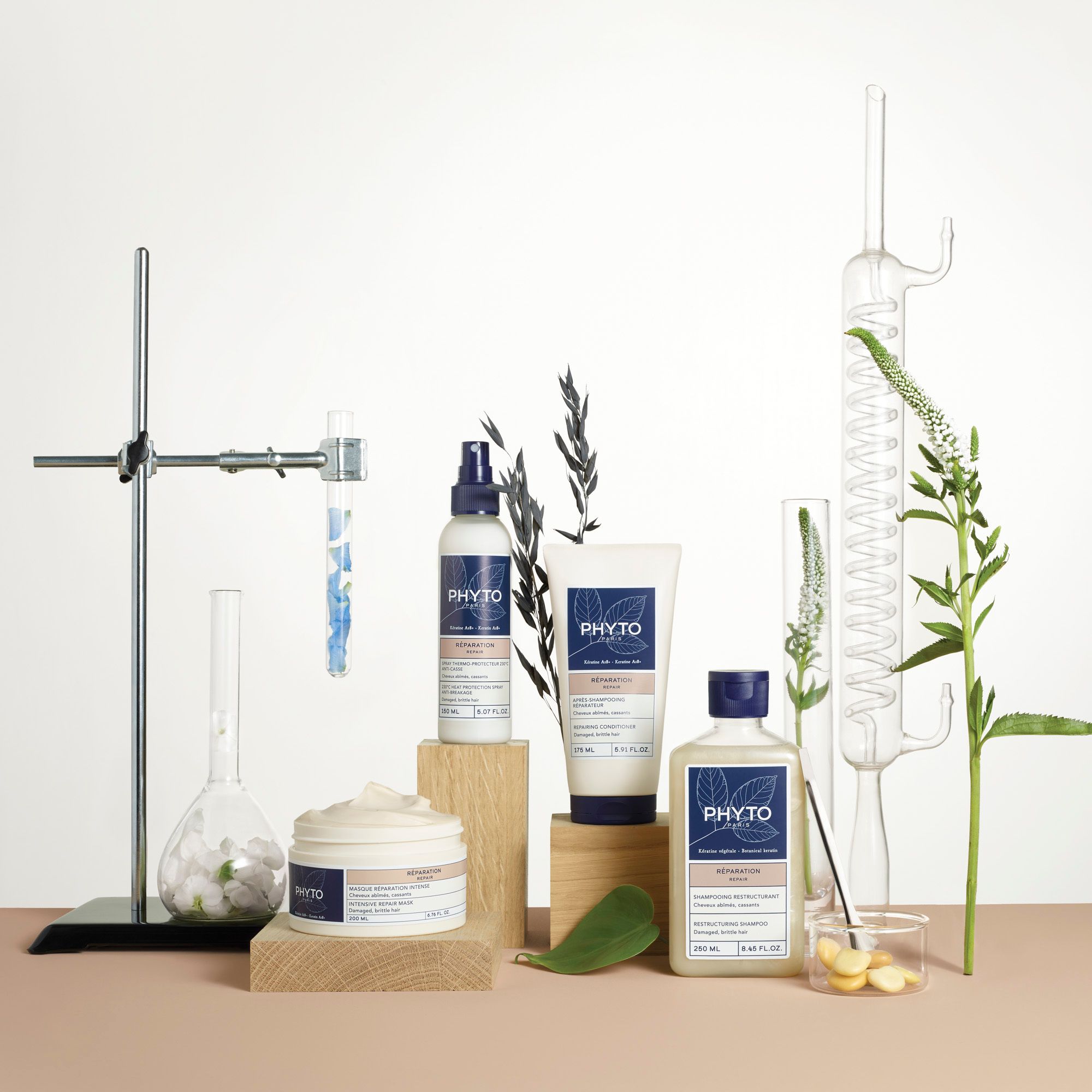 Présentation de produits. Plusieurs produits, dont du shampooing, sur des blocs de bois. Matériel de laboratoire et plantes en arrière-plan.