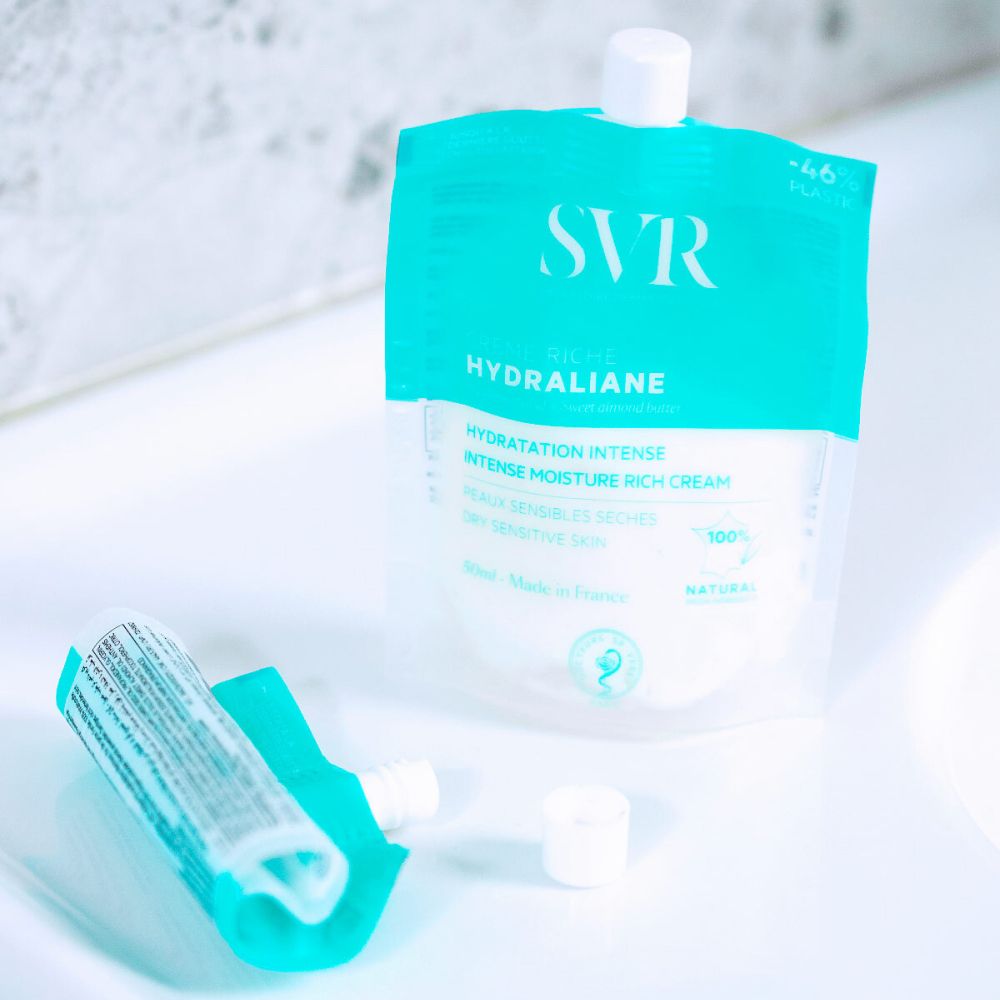 Sachet SVR Crème Riche Hydraliane. Emballage turquoise et blanc. Produit sur fond violet. Avec bouchon.