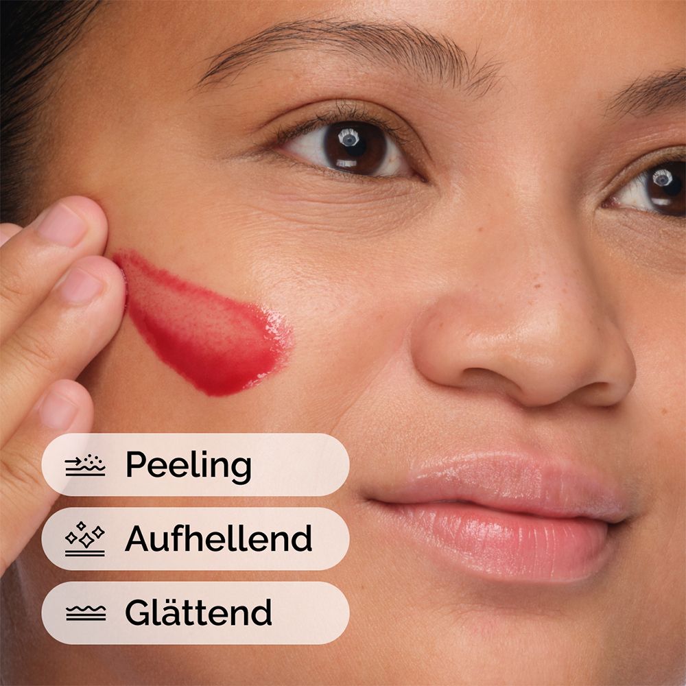 Personne appliquant du liquide rouge sur le visage. Texte: Exfolie, illumine, lisse.