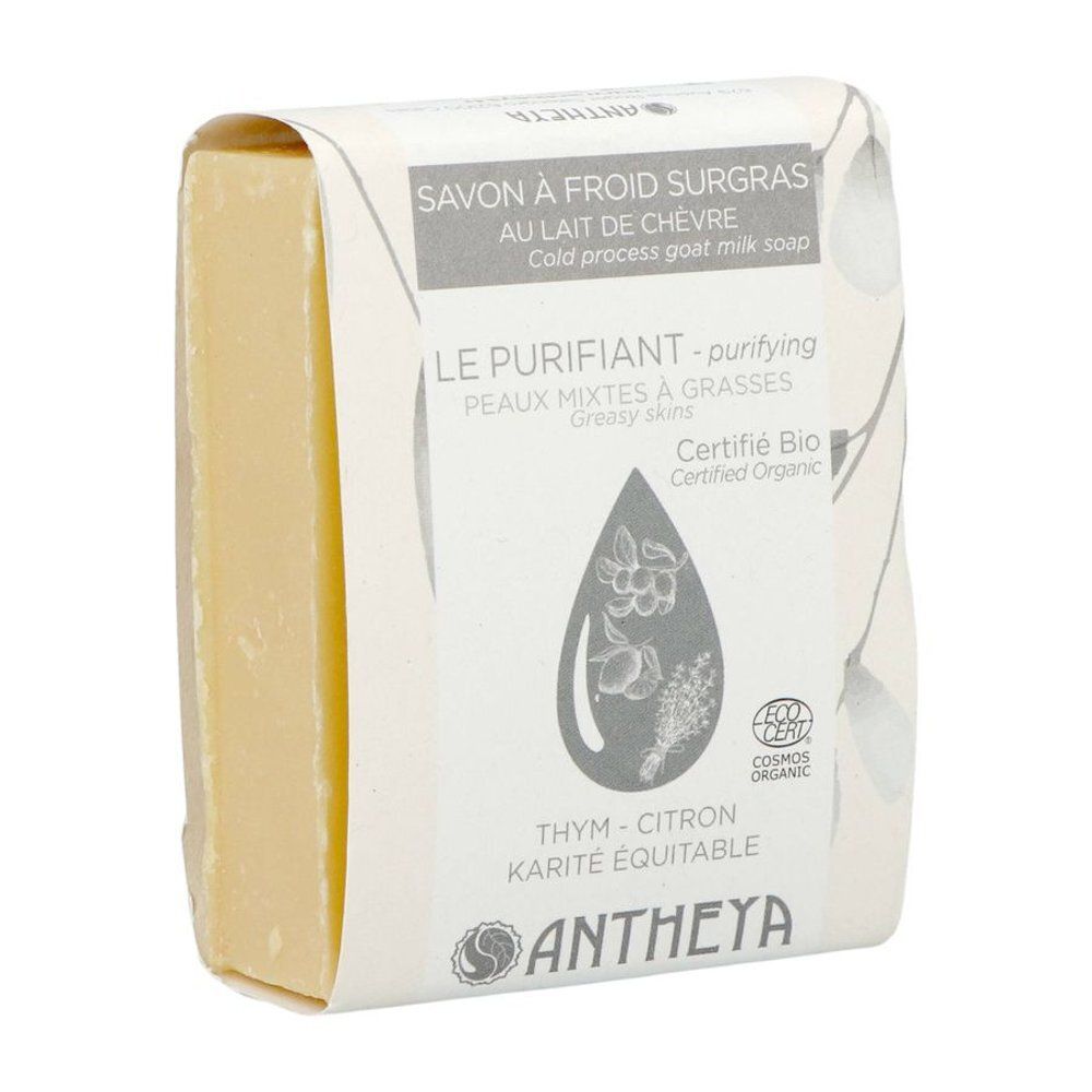 Un bloc de savon jaune dans un emballage blanc avec des motifs de plantes et de citron.