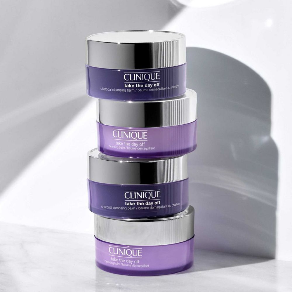 Quatre pots CLINIQUE Take the Day Off, empilés. Pots violets avec couvercles argentés.