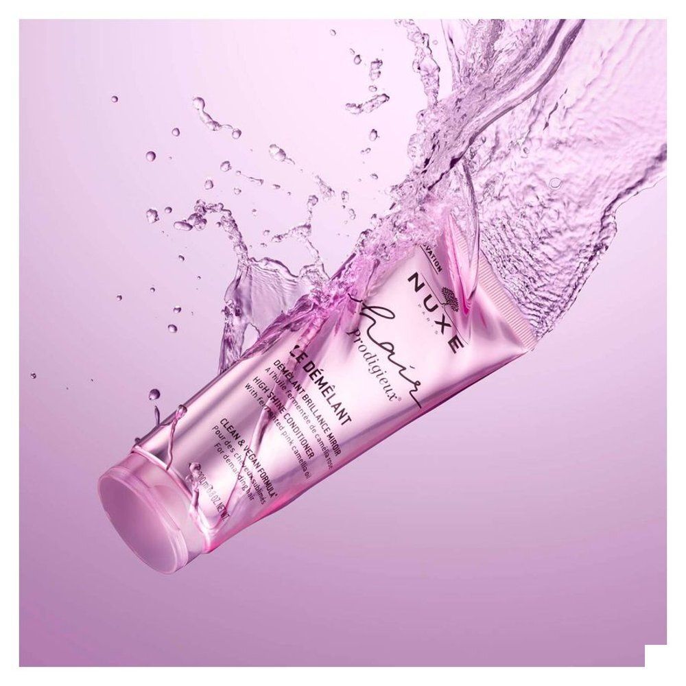 Tube NUXE Hair Prodigieux Le Démêlant dans une éclaboussure d'eau.