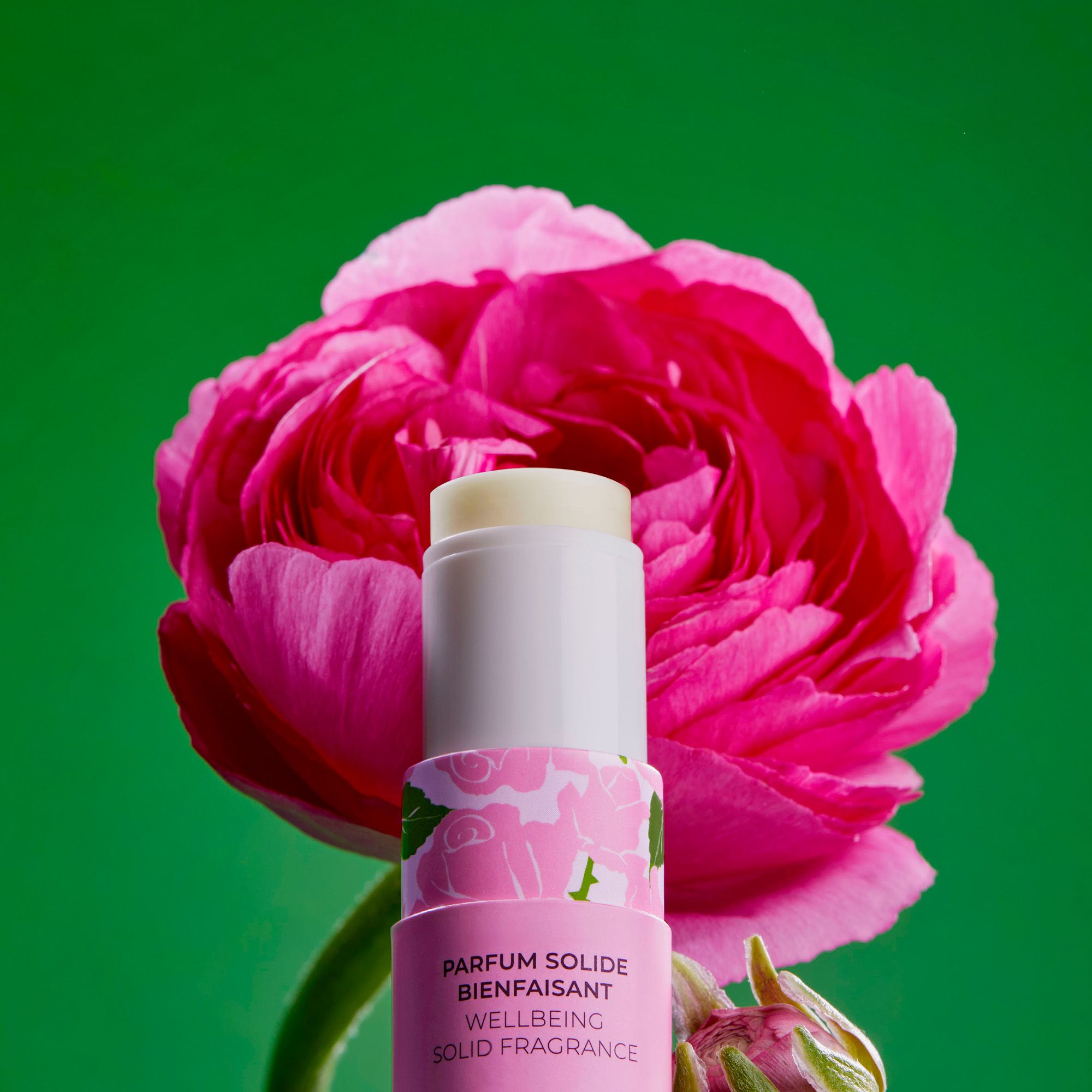 Produit emballé, devant fleur rose. Logo et texte: Roger&Gallet, Parfum Solide, Wellbeing Solid Fragrance. Pétale rose.