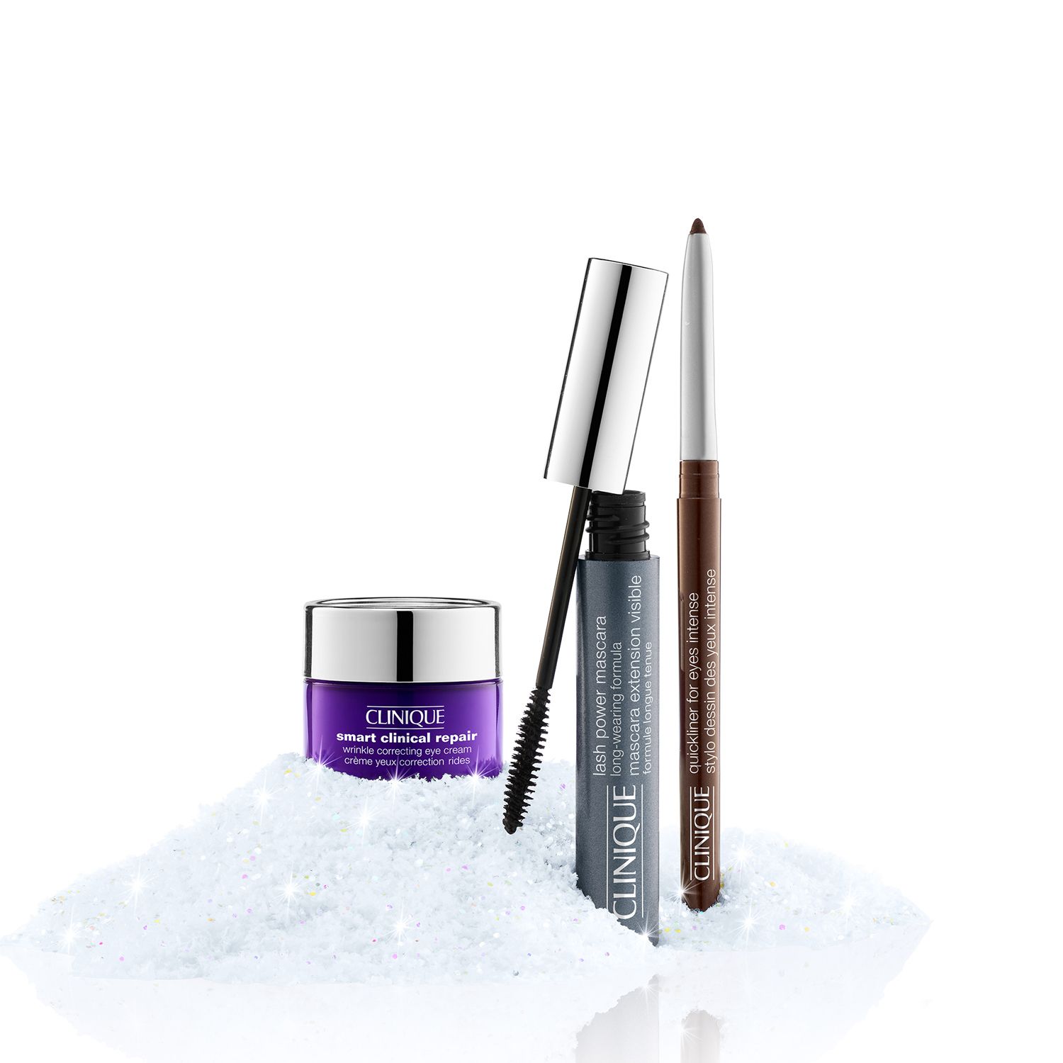 Crème pour les yeux, mascara et eye-liner. Produits sur fond blanc. Brosse de mascara visible. Eye-liner marron. Crème pour les yeux en pot violet.