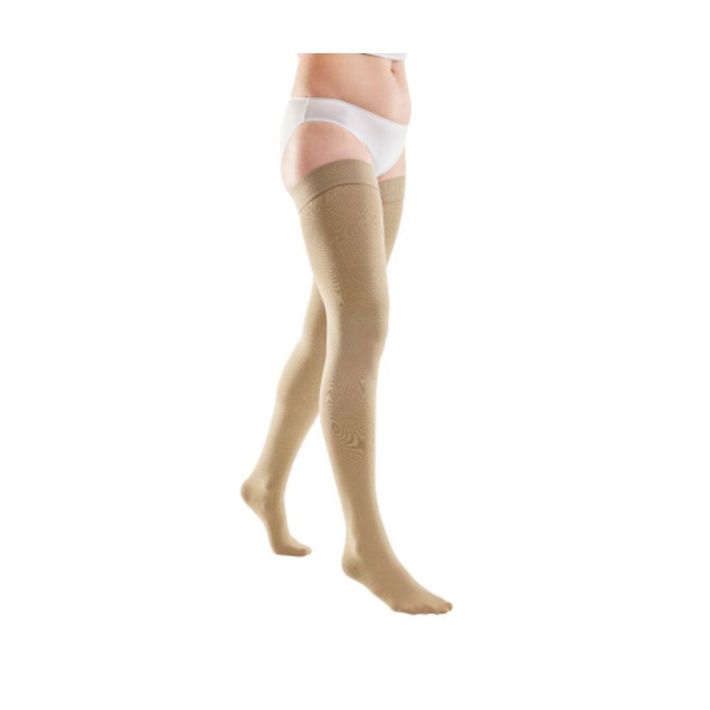 Bas de compression beiges jusqu'à la cuisse. Femme portant des bas et sous-vêtements blancs. Produit visible.