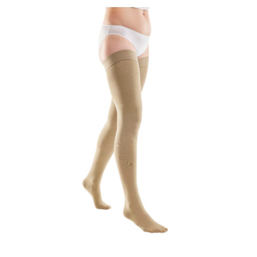 Bas de compression beige, cuisse haute. Motif. Personne portant des sous-vêtements blancs.