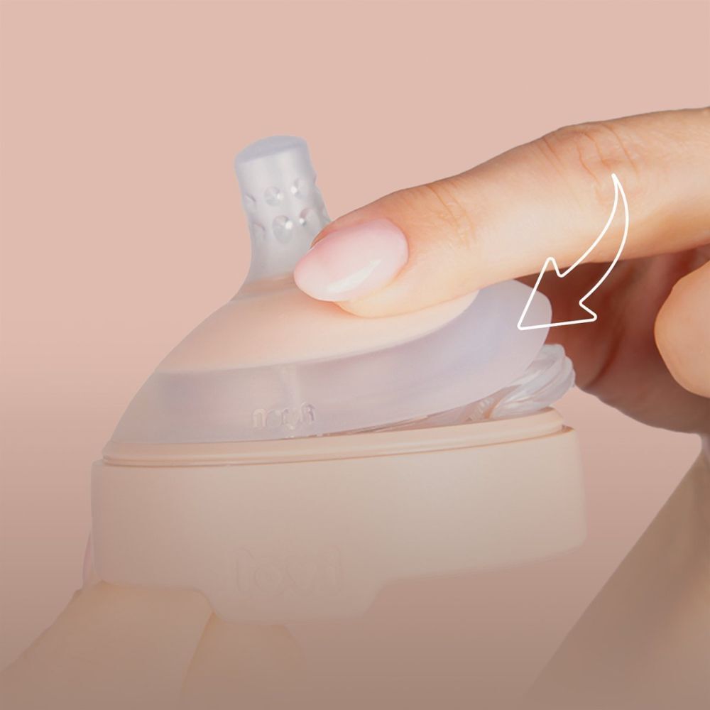 Main montrant comment fixer une tétine. Base rose, embout transparent.