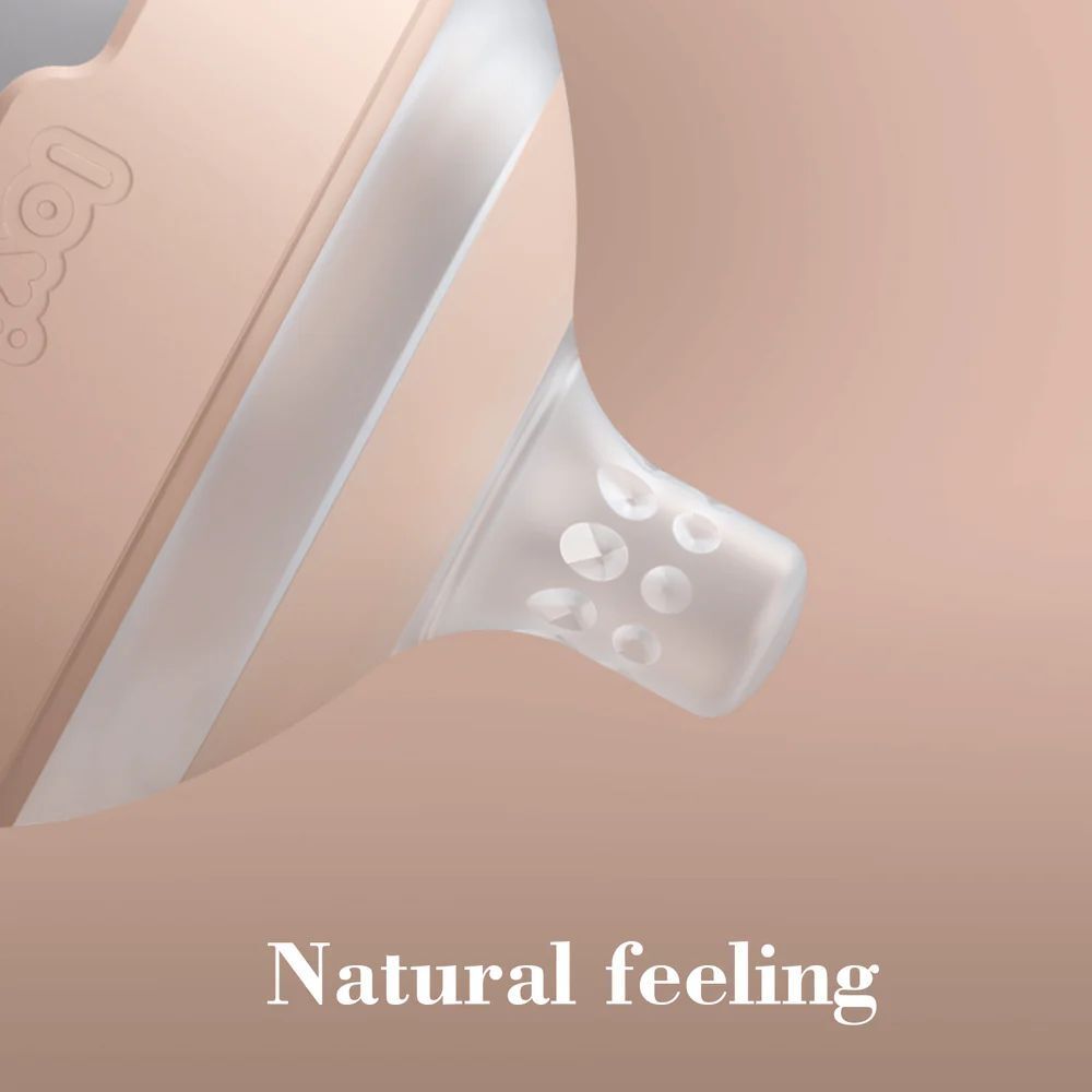 Gros plan sur la tétine. Embout en silicone transparent, base rose. Texte : Natural feeling.