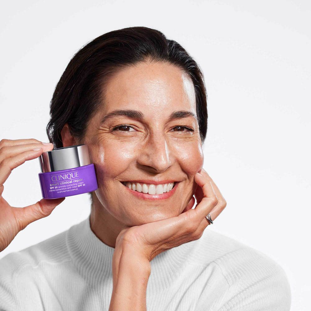 Femme tenant un pot violet de crème hydratante Clinique SPF 20.