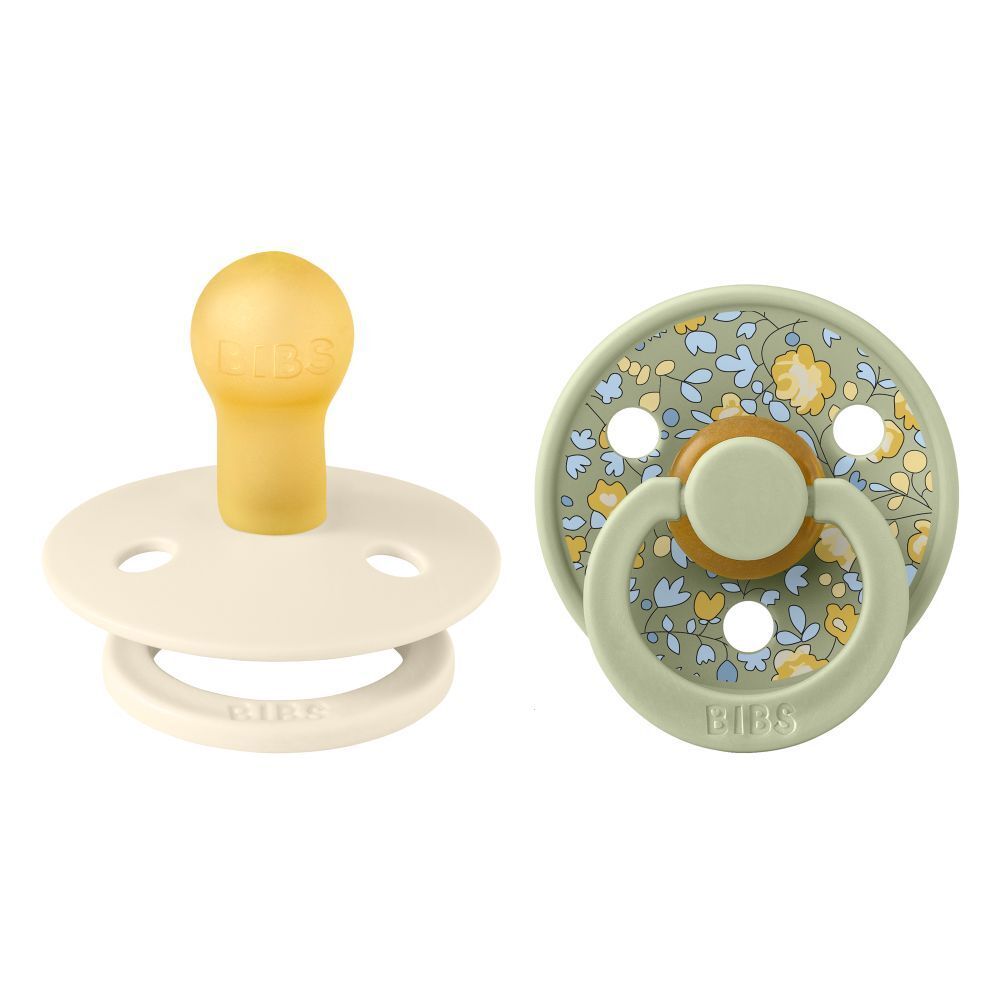 Deux sucettes. Tétine jaune, bouclier crème. Bouclier vert, floral.