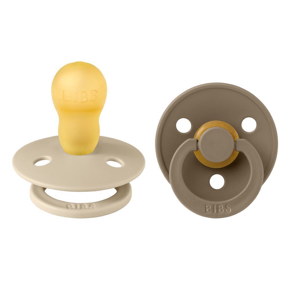 Deux sucettes BIBS. Une sucette beige clair, une marron foncé. Les deux avec anneau et tétine. Logo BIBS visible.