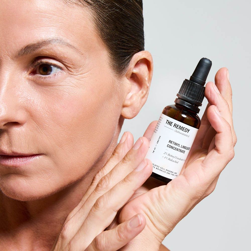 Flacon de sérum THE REMEDY Retinyl Linoleate Concentrate tenu par une femme.