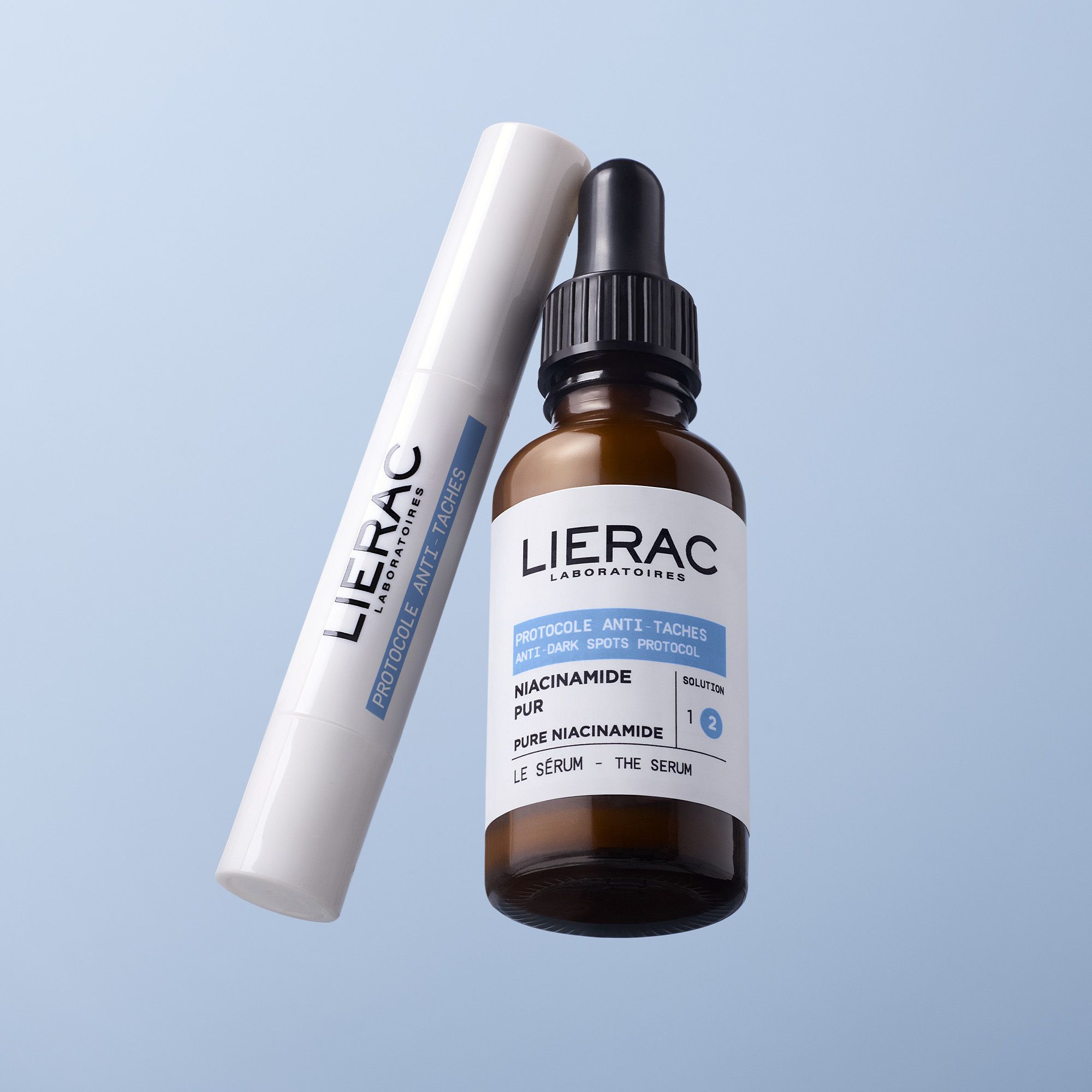 Flacon en verre brun avec pipette noire. Étiquette avec informations produit. Marque : Lierac.