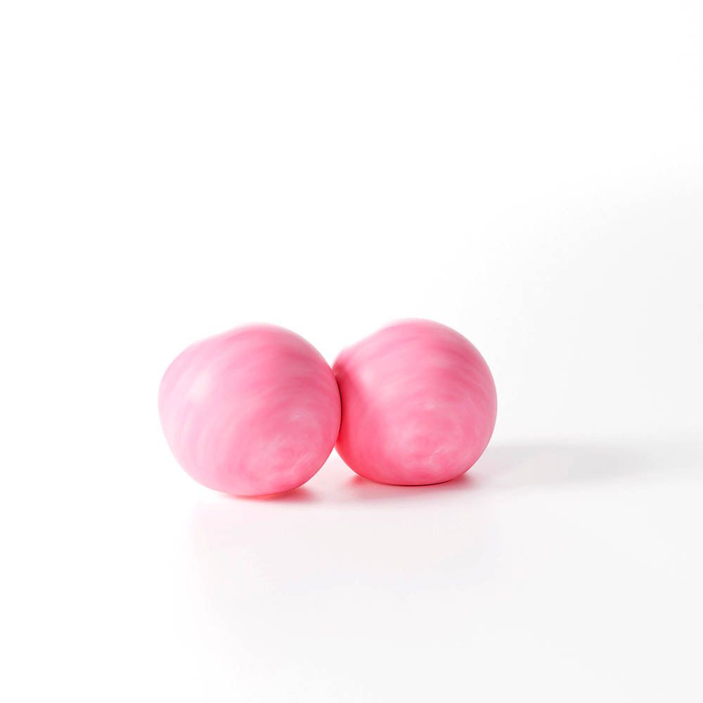 Deux bouchons d'oreille roses. Forme ronde, surface légèrement irrégulière. Sur fond blanc.
