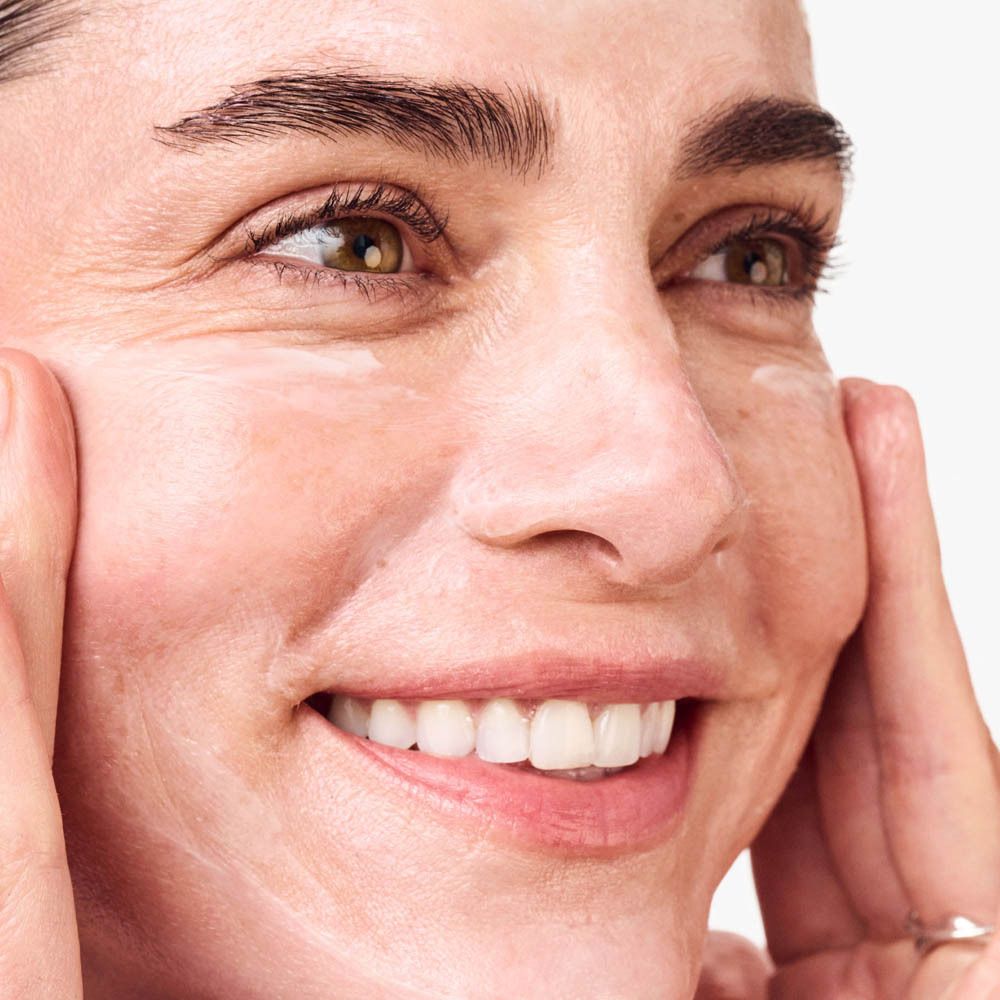 Gros plan d'une femme appliquant une crème pour le visage.