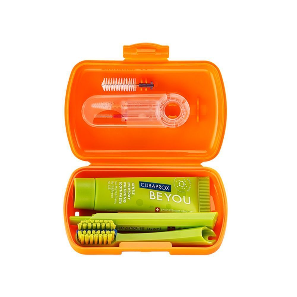 Trousse de voyage orange ouverte. Contient brosse à dents, dentifrice et brossettes. Curaprox.