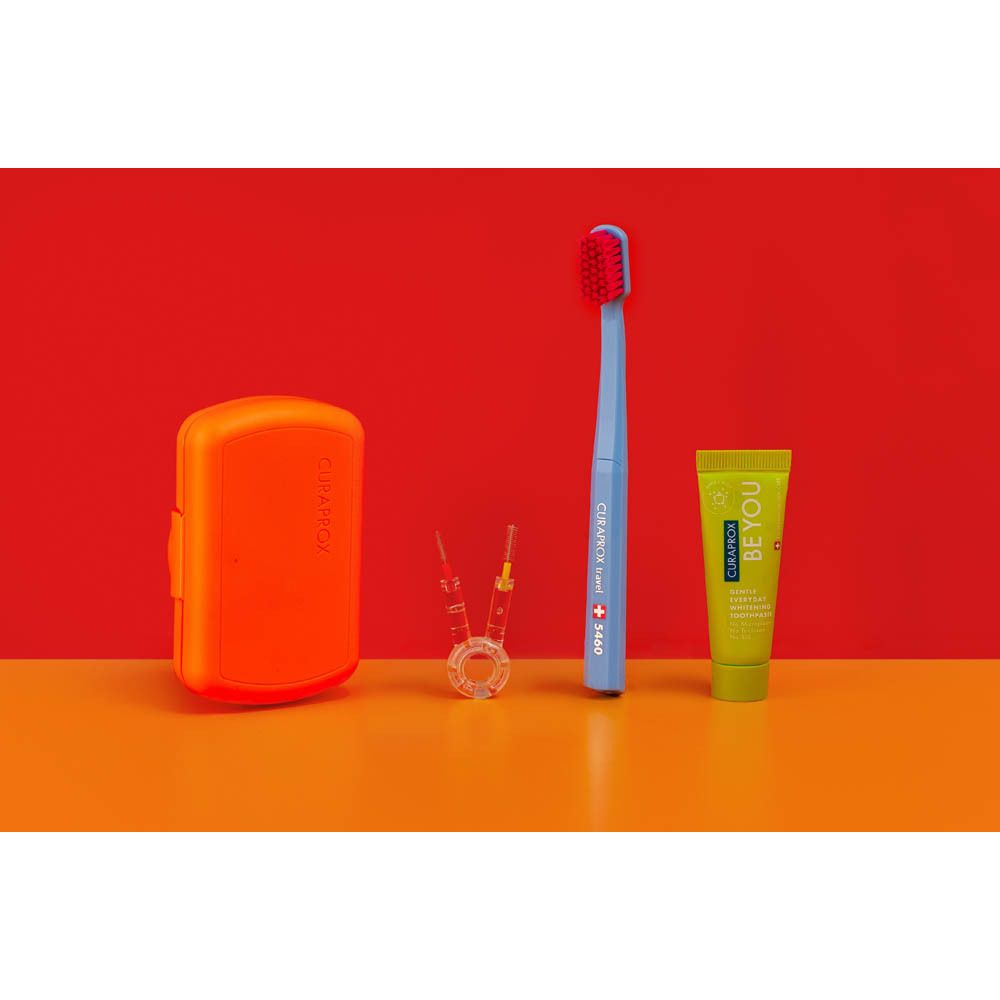 Un set de brossage Curaprox bleu avec tête de brosse rouge, deux brosses interdentaires, un étui de rangement orange et un tube de dentifrice jaune.