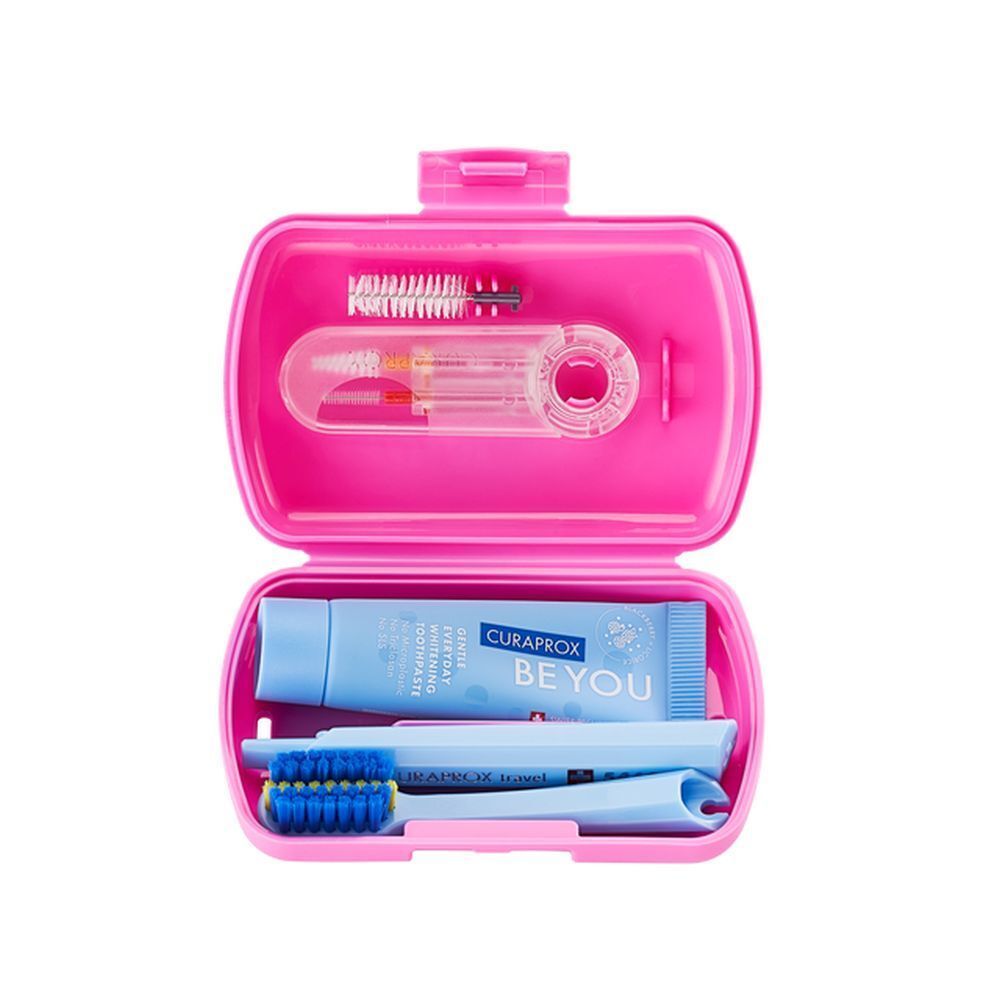 Trousse de voyage rose ouverte. Contient brosse à dents, dentifrice, brossettes interdentaires. Marque Curaprox.