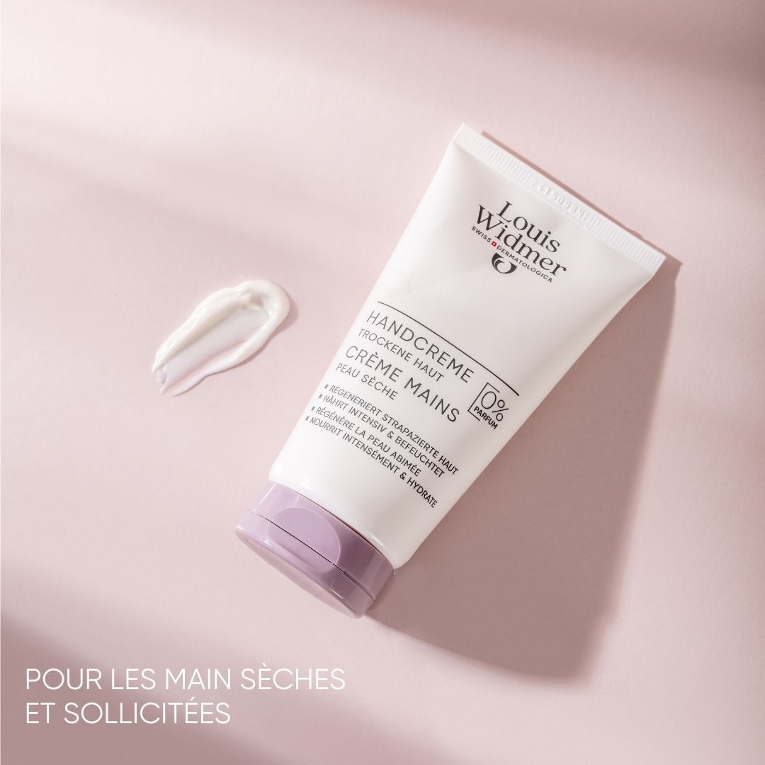 Tube de crème pour les mains avec une noisette de crème à côté. Inscription: Louis Widmer, Handcreme, peau sèche, 0% parfum. Bouchon violet.