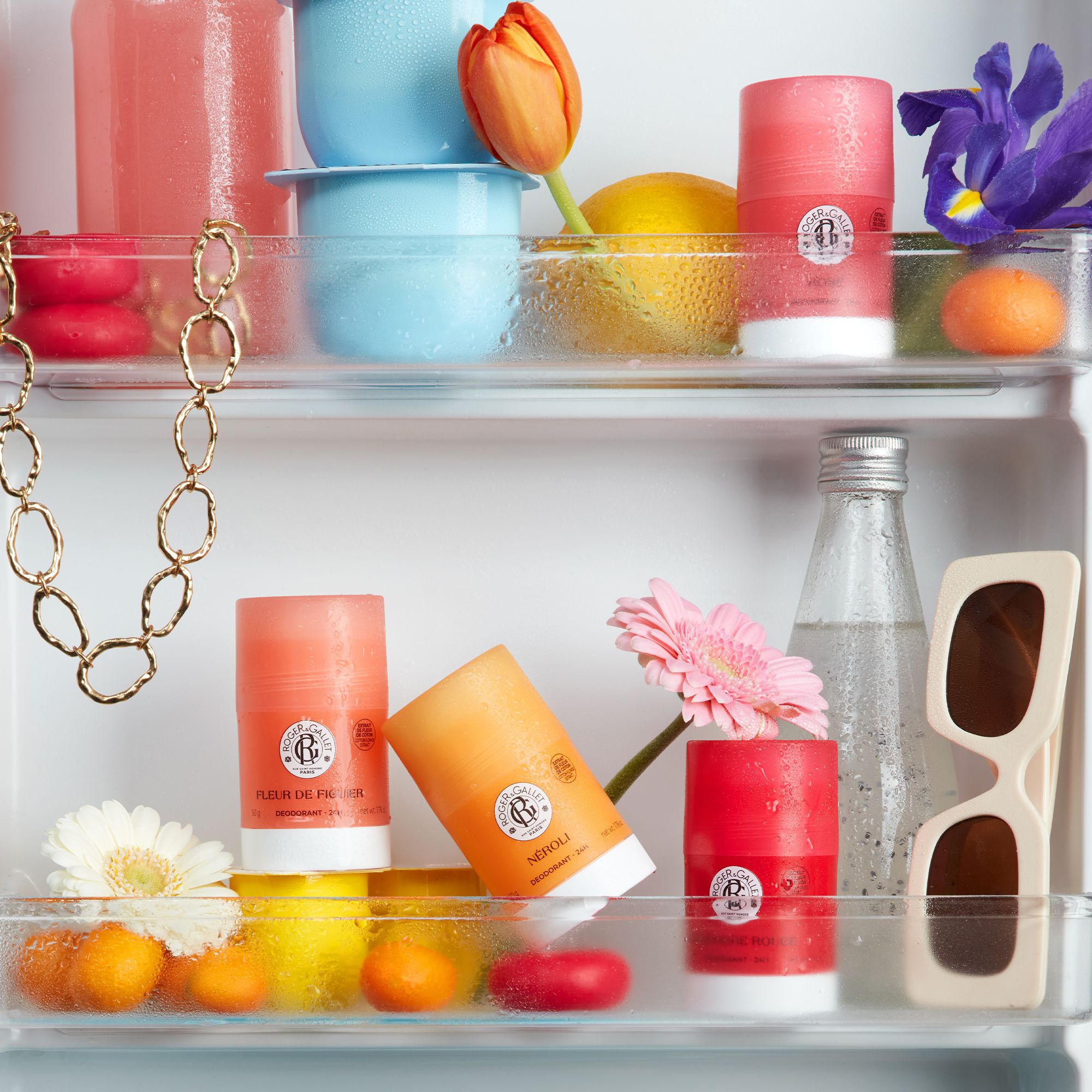 Réfrigérateur avec produits. Déodorants Roger & Gallet, lunettes de soleil, fleurs, fruits. Différentes couleurs et formes.