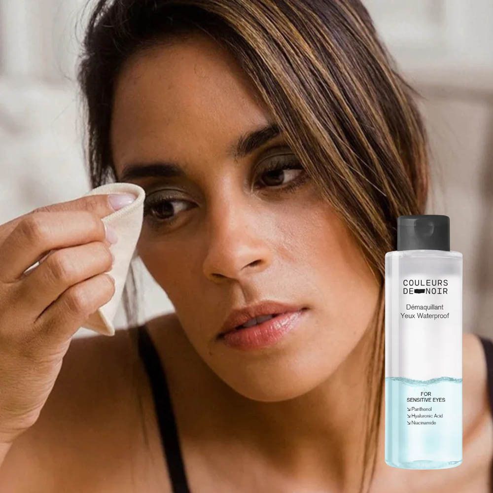 Femme se démaquillant avec un coton. Bouteille Démaquillant Yeux Waterproof à côté.