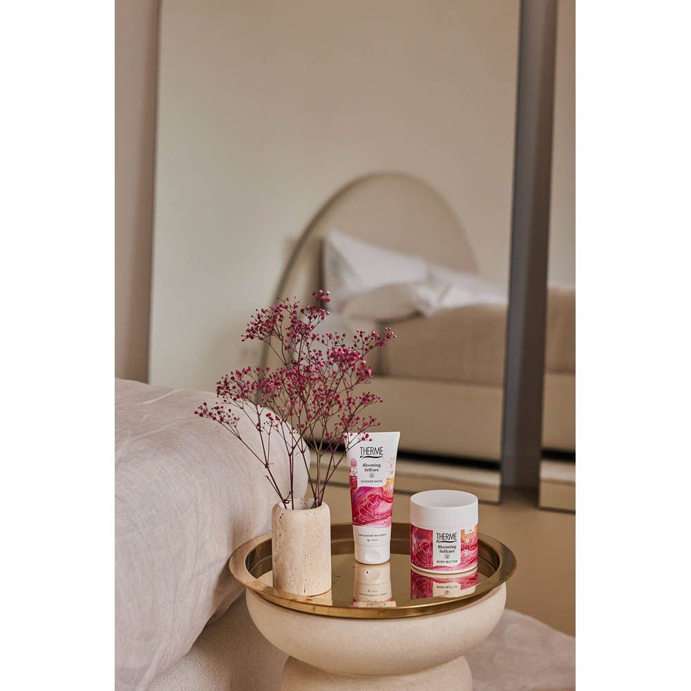 Produit sur un plateau avec vase et miroir en arrière-plan. Fleurs roses.