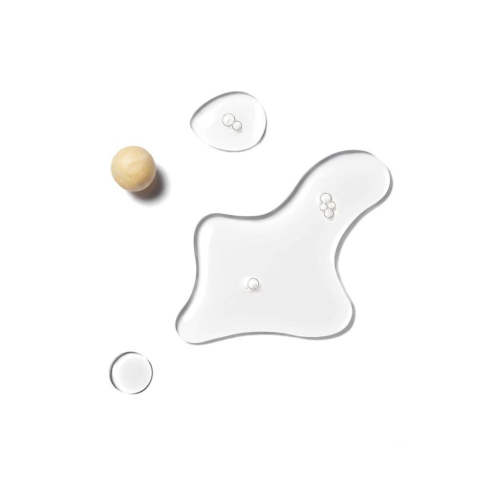 Gouttes de liquide et une bille sur fond blanc. Liquide avec de petites bulles.
