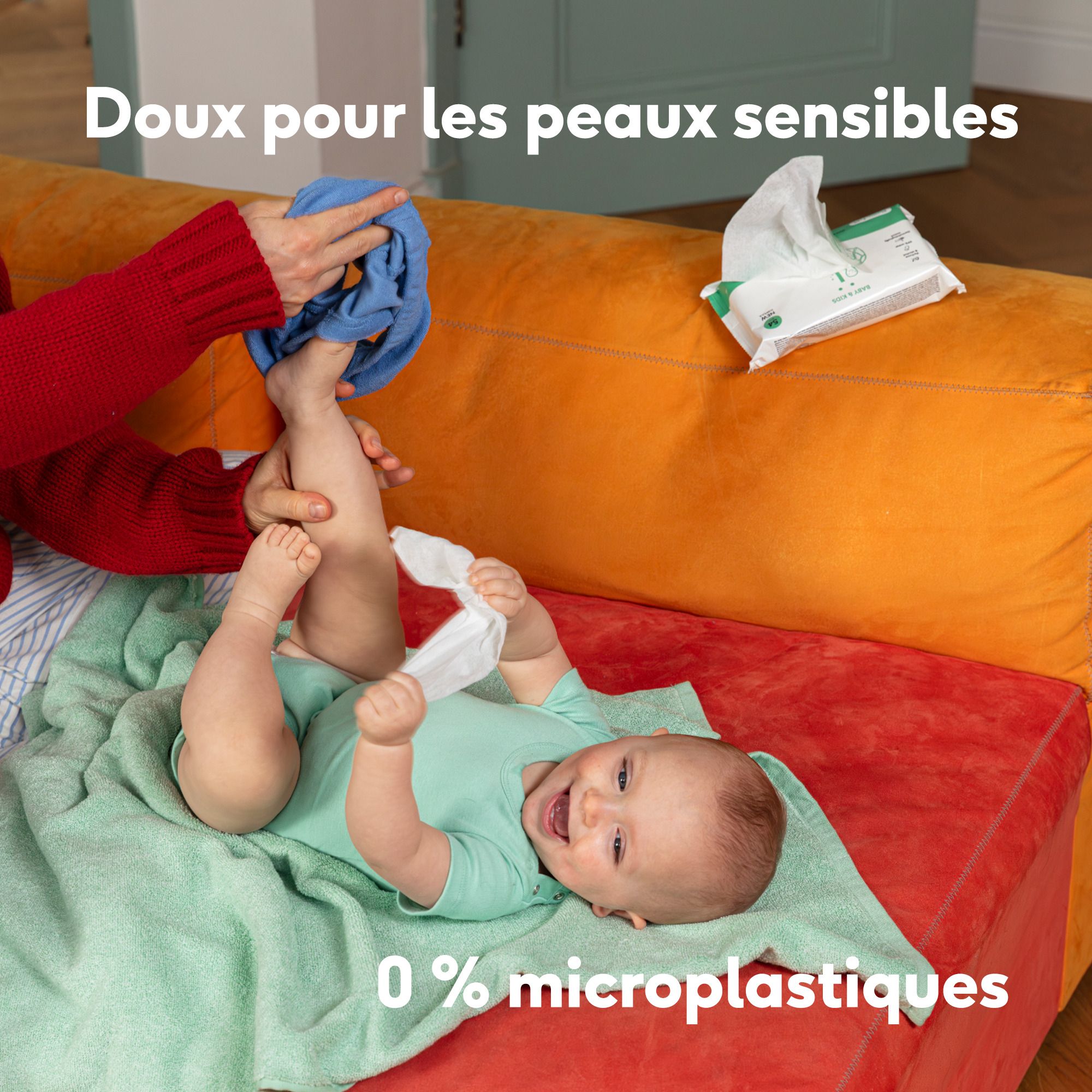 Pied de bébé séché avec une serviette bleue, lingettes humides à côté.