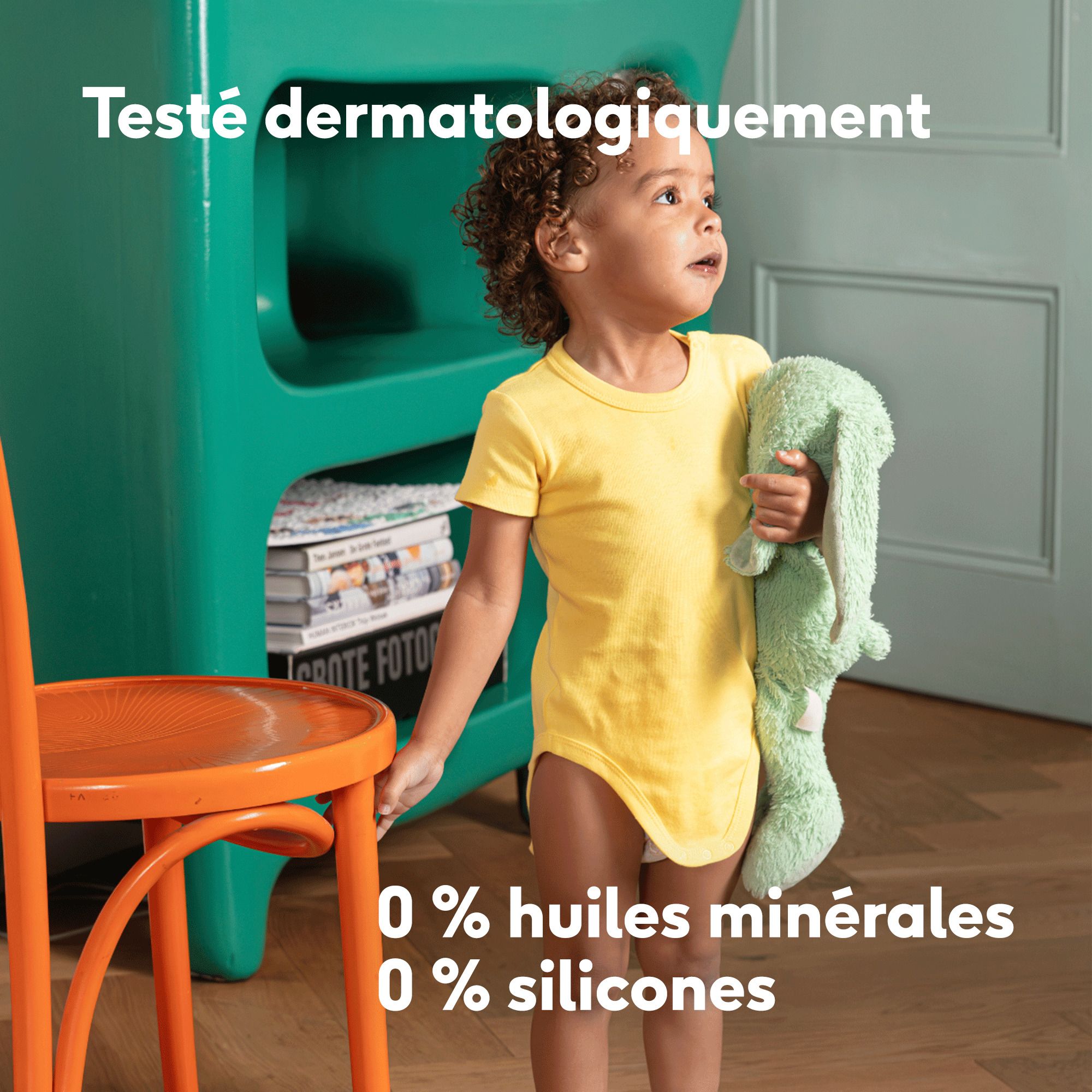 Enfant aux cheveux bouclés. Texte : Alles wat je baby nodig heeft. Niets meer.