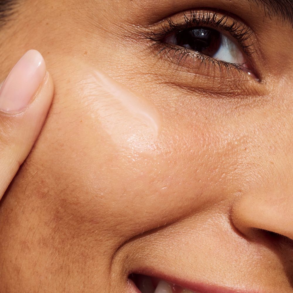 Personne appliquant du sérum sur le visage. Nom de la marque ou du produit non visible.