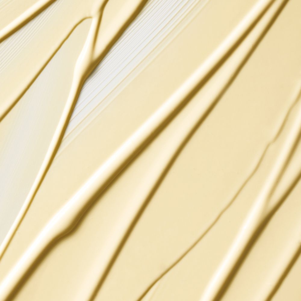 Gros plan d'une lotion crème appliquée en stries diagonales sur une surface.