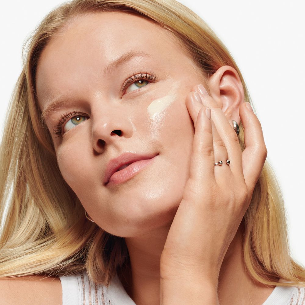 Femme appliquant de la crème sur son visage. Produit : Clinique Dramatically Different Moisturizing Lotion.
